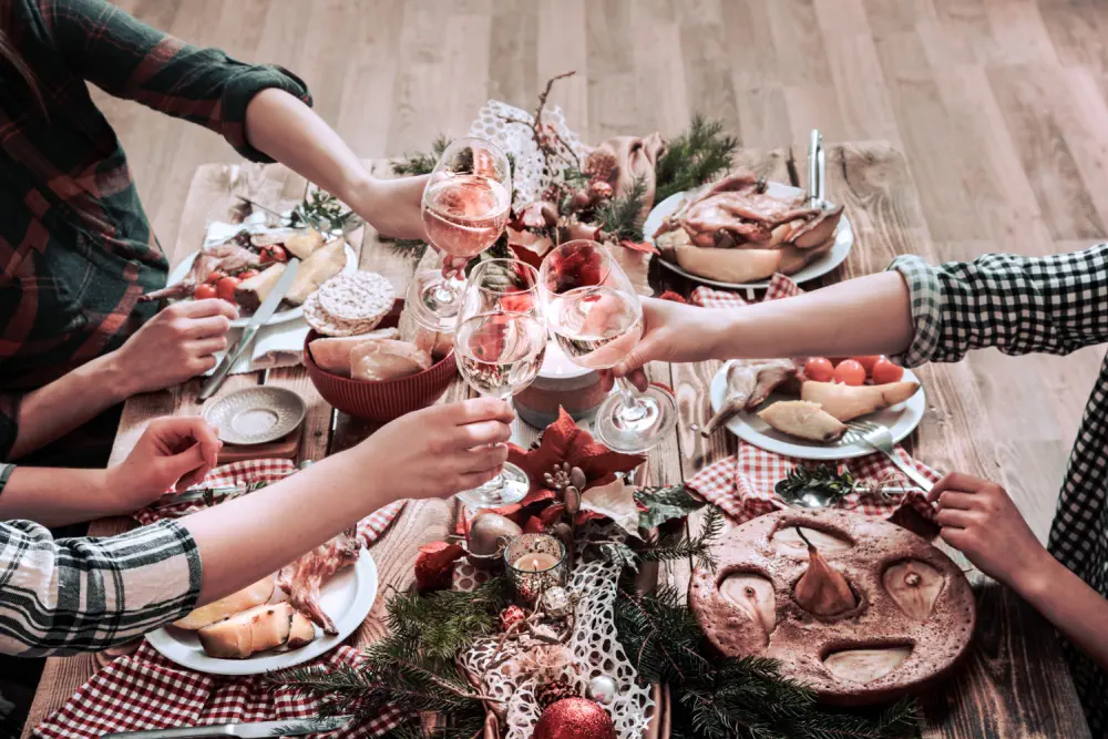 Four people toast with wine glasses over a festive dinner table.