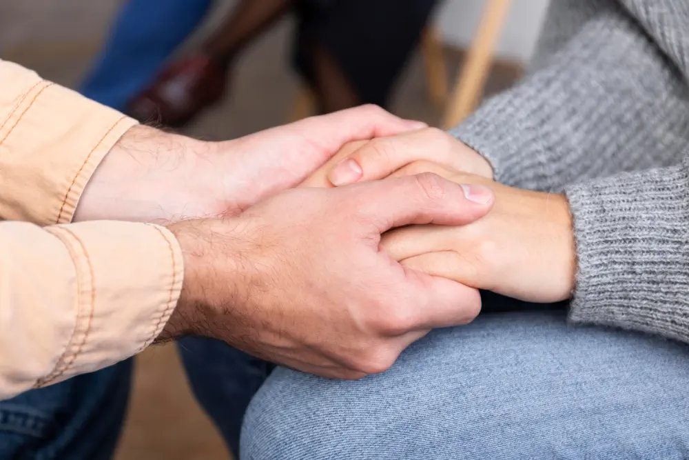Two people holding hands in a supportive gesture.