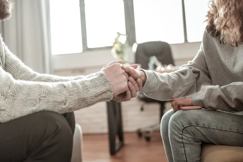 Two people holding hands, representing emergency support and compassion.